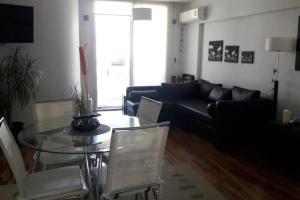 uma sala de estar com uma mesa de vidro e um sofá preto em Rosario siempre estuvo cerca em Rosário