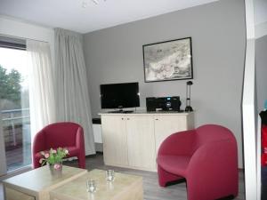 ein Wohnzimmer mit 2 roten Stühlen und einem TV in der Unterkunft Kaapshoff 32 in Hollum