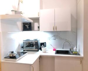 cocina blanca con fregadero y microondas en Jasmine Studio, en Radom