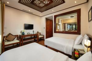 a hotel room with two beds and a television at Hanoi Nostalgia Hotel & Spa in Hanoi