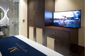 um quarto com uma televisão numa cómoda com uma cama em Millennium Hue Hotel em Hue