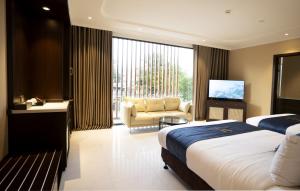 une chambre d'hôtel avec deux lits et un canapé dans l'établissement Millennium Hue Hotel, à Hue