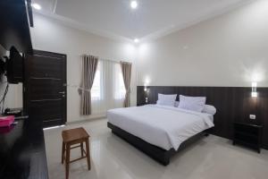 una camera con letto bianco e TV di Kelayang Beach Hotel a Tanjungbinga