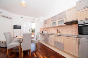 una cocina con armarios de madera, mesa y sillas en Apartments PREMANTURA DOM, en Premantura