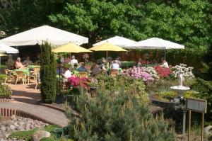 einen Garten mit Tischen und Sonnenschirmen in der Unterkunft Hotel "Am Werl" in Bad Saarow