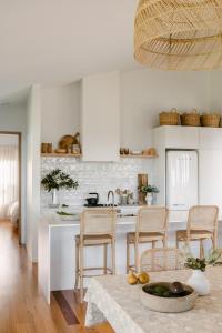 a kitchen with white cabinets and a table with chairs at Upland Farm Luxury Cabins, Denmark Western Australia in Denmark