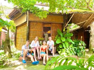 a group of people sitting in front of a house at Under The Coconut Tree Hoi An Homestay in Hoi An