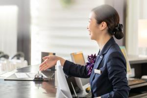 uma mulher sentada numa secretária num escritório em Hotel JAL City Haneda Tokyo em Tóquio