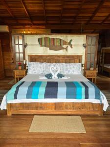 Hotel Pousada Praia do Farol في إيلها دو ميل: غرفة نوم بسرير كبير عليها شرائط زرقاء وبيضاء