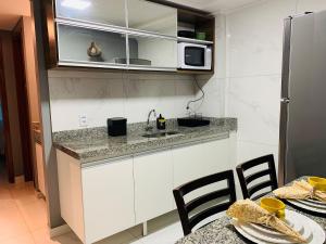 a kitchen with a sink and a microwave and a table at Blue Sunset Prime com vista para mar in João Pessoa
