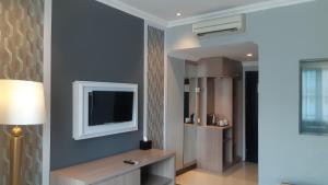 sala de estar con TV en la pared en Luminor Hotel Palembang by WH, en Palembang