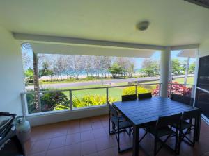 a porch with a blue table and a large window at 6 Ulysses - Spacious Beachfront Apartment in Mission Beach