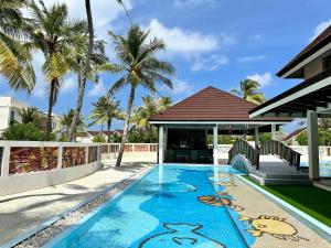 - une piscine en face d'une maison avec des palmiers dans l'établissement OBLU XPERIENCE Ailafushi - All Inclusive with Free Transfers, à Malé