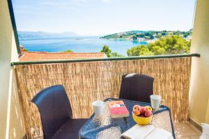 a table with a bowl of fruit on a balcony at Eco Sunshine Apartments Lumbarda in Lumbarda