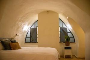 a bedroom with a white bed and two windows at Cozy Heritage Home Jerusalem in Jerusalem