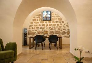 a dining room with a stone wall and a table and chairs at Cozy Heritage Home Jerusalem in Jerusalem