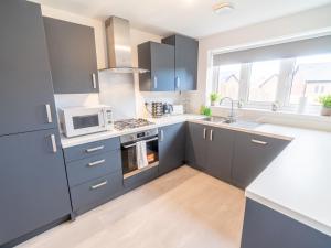 a kitchen with blue cabinets and a microwave at Pass the Keys Centrally located beautiful 3 bed new build home in Nottingham