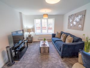 a living room with a blue couch and a tv at Pass the Keys Modern 3-Bed Home with Garden & Free Parking in Nottingham