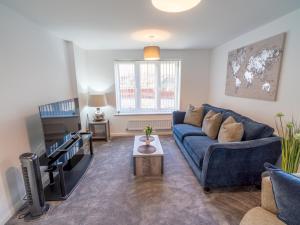 a living room with a blue couch and a tv at Pass the Keys Centrally located beautiful 3 bed new build home in Nottingham