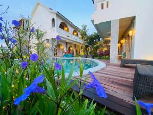 a house with a swimming pool and purple flowers at MAHALONA BALI STAY in Canggu