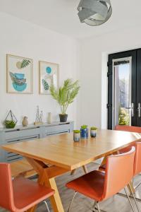 a dining room with a wooden table and orange chairs at Townhouse in Ebbsfleet sleeps 9 with free parking in Greenhithe