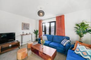 a living room with a blue couch and a table at Townhouse in Ebbsfleet sleeps 9 with free parking in Greenhithe