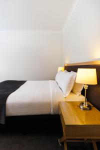 1 dormitorio con 1 cama y 1 mesa con lámpara en Chimes Spa Retreat, en Denmark