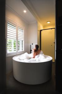 a man sitting in a bath tub in a room at Chimes Spa Retreat in Denmark