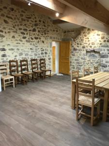 a room with wooden tables and chairs and a stone wall at appartement de l'église et du château 2 à 15 personnes in Avène