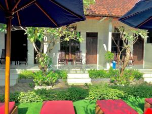 a house with an umbrella in the front yard at Wahyu Homestay 1 in Nusa Lembongan