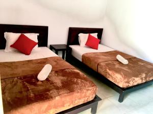 two beds in a hotel room with red pillows at Wahyu Homestay 1 in Nusa Lembongan