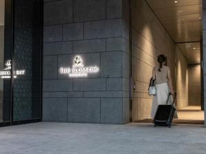 a woman walking through a building with a suitcase at THE BLOSSOM KUMAMOTO in Kumamoto