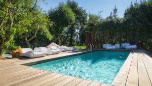 una piscina con muebles blancos junto a una terraza de madera en LA DAMA DEL BOSCO 8&3, Emma Villas, en Capriglia