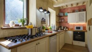 Una cocina con estufa, fregadero y ventana. en LA DAMA DEL BOSCO 8&3, Emma Villas, en Capriglia