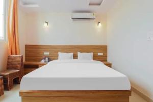 a bedroom with a large white bed and a desk at Hotel Rabbit Hut in Dehradun
