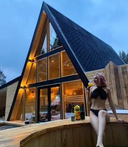 a woman in a bikini sitting on a ledge in front of a house at Cabana Tinovo in Dornişoara