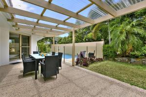 a patio with a table and chairs under a pergola at 21 David Street Noosa Heads in Noosa Heads