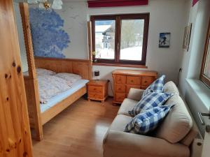 ein Schlafzimmer mit einem Bett, einem Sofa und einem Fenster in der Unterkunft Bauernhaus im Permakultur-Garten in Sankt Johann in Tirol
