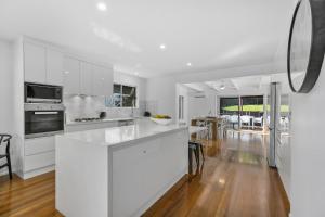 a kitchen with white appliances and wooden floors at 21 Nairana Rest Noosa Heads in Noosa Heads