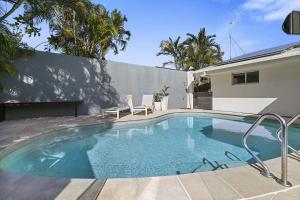 a swimming pool with two chairs and a house at 21 Nairana Rest Noosa Heads in Noosa Heads