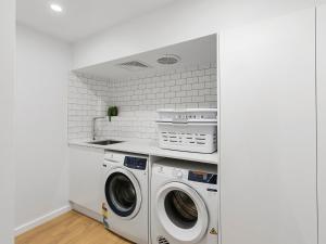 a white laundry room with a washer and dryer at 21 Nairana Rest Noosa Heads in Noosa Heads