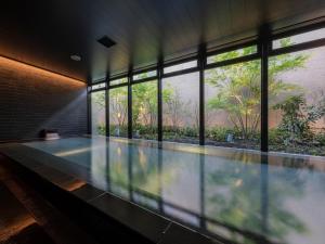 a swimming pool in a building with windows at THE BLOSSOM KUMAMOTO in Kumamoto