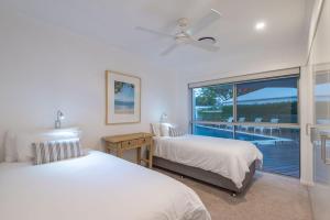 two beds in a bedroom with a view of a pool at 21 Wesley Court Noosa Sound in Noosa Heads +29 photos