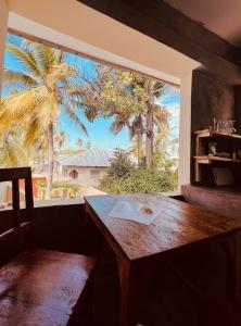 stół i okno z widokiem na palmę w obiekcie Freshi Residence w mieście Jambiani