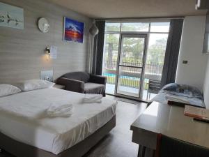 um quarto de hotel com uma cama e uma cadeira e uma janela em Le George Motel em Port Macquarie