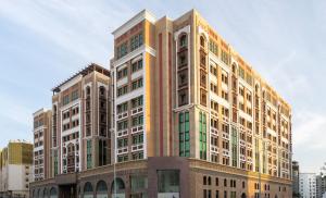 un edificio alto con muchas ventanas en una ciudad en La Maison Hotel Doha, en Doha