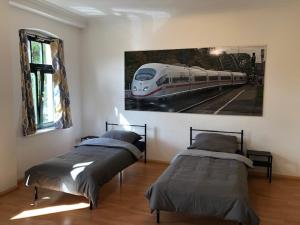 een slaapkamer met 2 bedden en een schilderij van een trein bij Ferienwohnung Nordluft in Erfurt