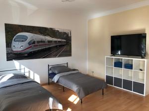 een slaapkamer met 2 bedden en een treinschilderij aan de muur bij Ferienwohnung Nordluft in Erfurt