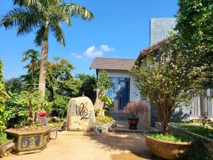 a garden with a house and a palm tree at T'Farmstay villa and resort Buon Ma Thuot City in Buon Ma Thuot