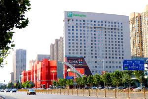 um grande edifício numa cidade com carros na rua em Holiday Inn Panjin Aqua City, an IHG Hotel em Panjin
